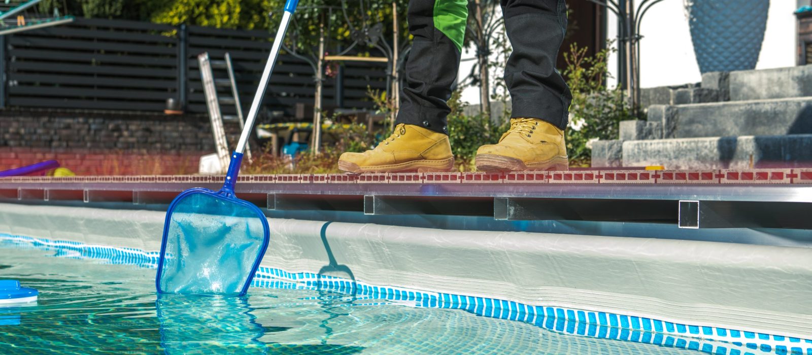 Poolside Maintenance Worker Cleaning Water Surface with a Net. Keeping Swimming Pool Clean.